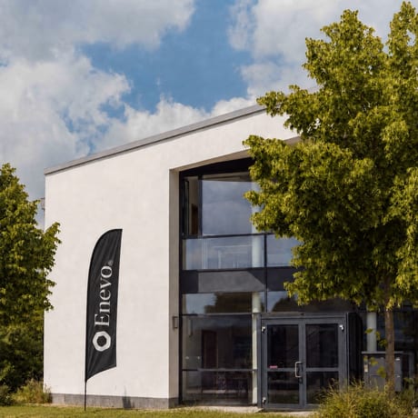 Bürogebäude von Enevo in Freising, davor eine Beachflag mit dem Enevo-Zeichen.